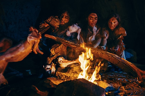 Steinzeitmenschen nach der Jagd am Feuer.